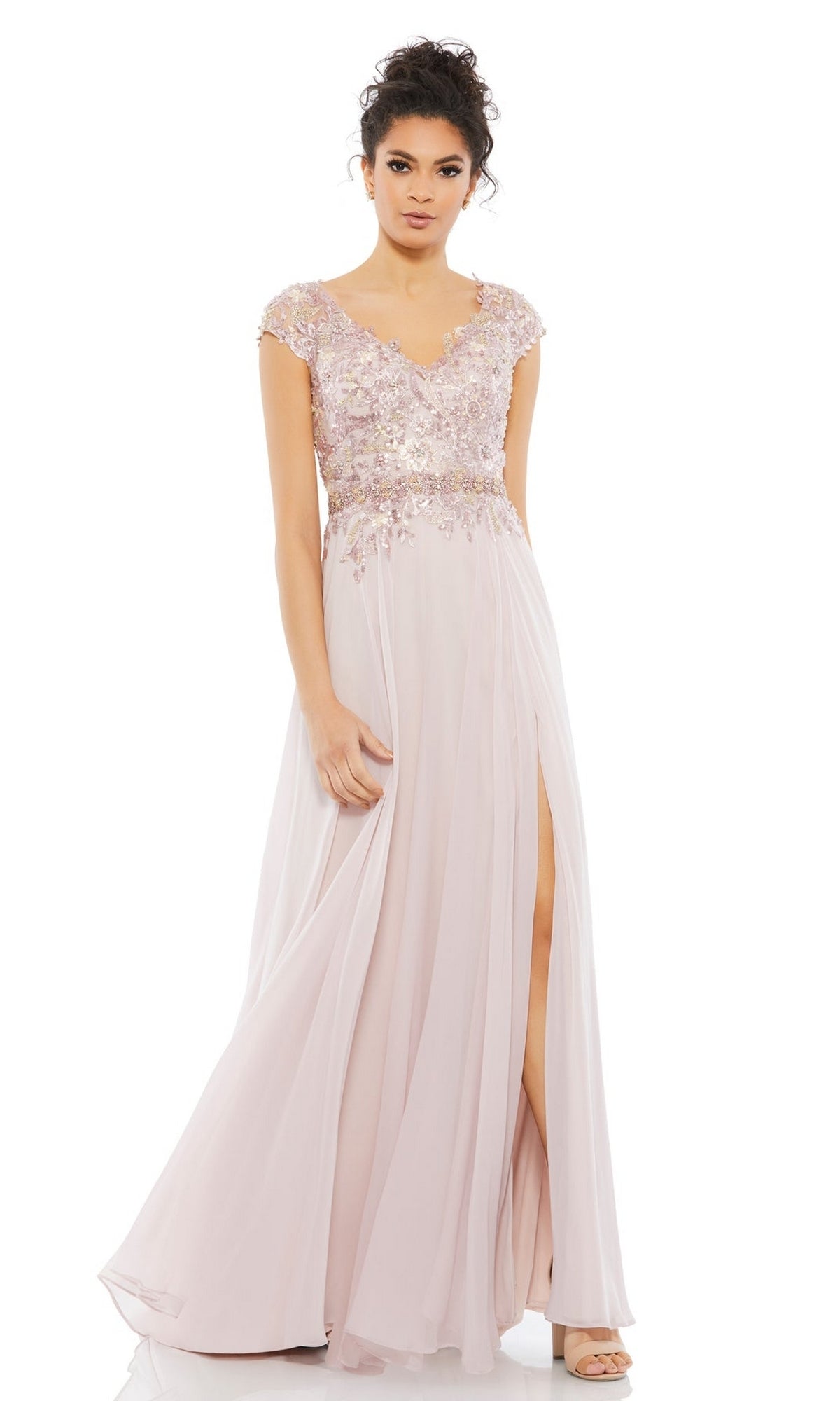 A woman wearing the Mac Duggal 79365 Cap-Sleeve Long Formal Dress in light pink, featuring an embellished bodice, floral accents, a thigh-high slit, and paired with open-toe heels.